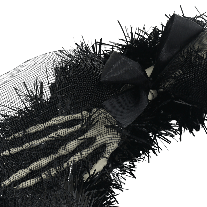 detail shot of skeleton hands on tinsel wreath with silk bow and organaza mesh material on top