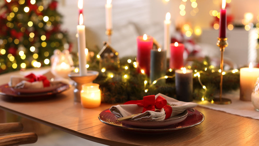 christmas ining table with red and white candles, red festive plates and napkins with christmas tree in background