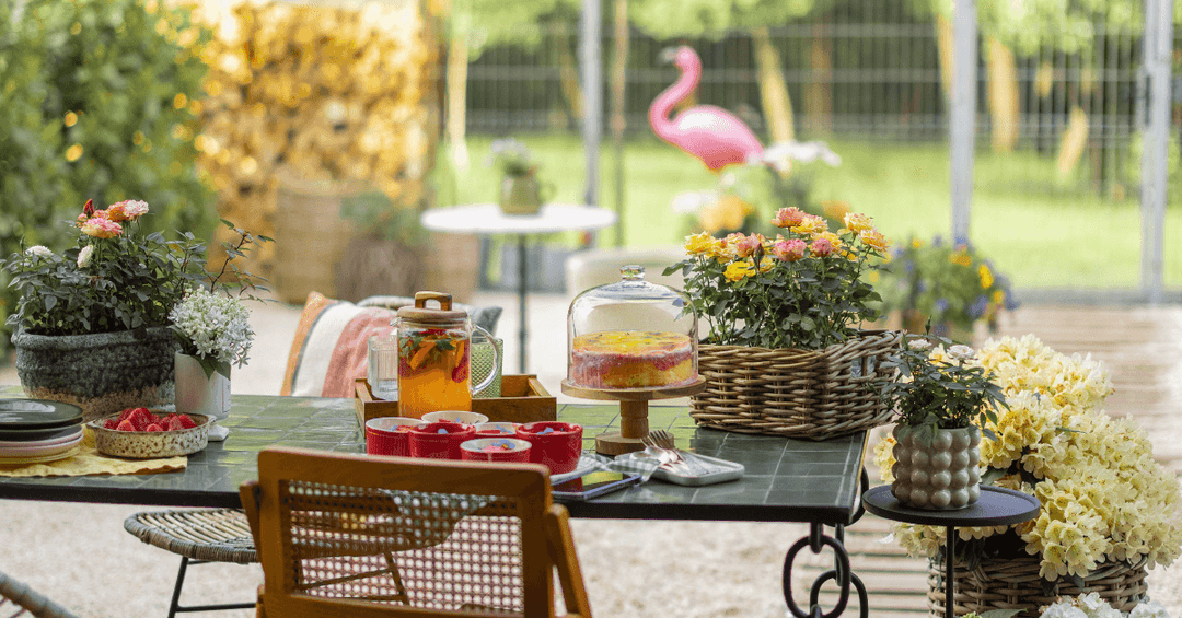 garden dining table featuring cake stand, decorative flowers and fresh summer drinks