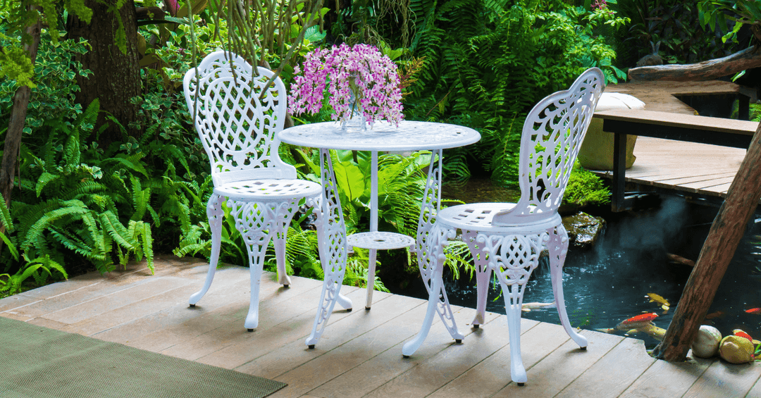 white cast aluminium antique bistro set in white finish beside koi pond in garden area