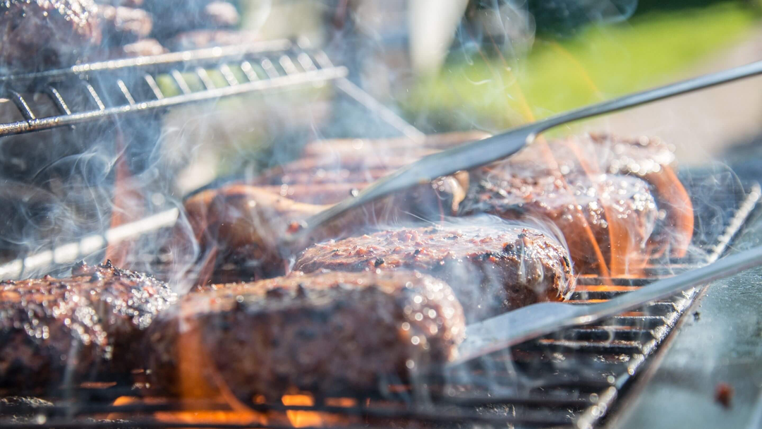 burgers on a bbq being flipped by barbecue tool