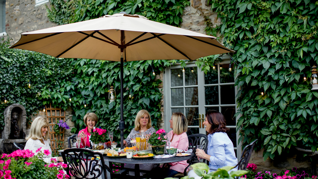 group of ladies having a garden get together under a beige coloured parasol