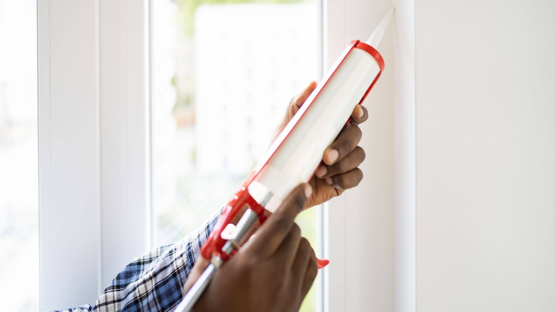 person using silicone gun to seal corners in the home