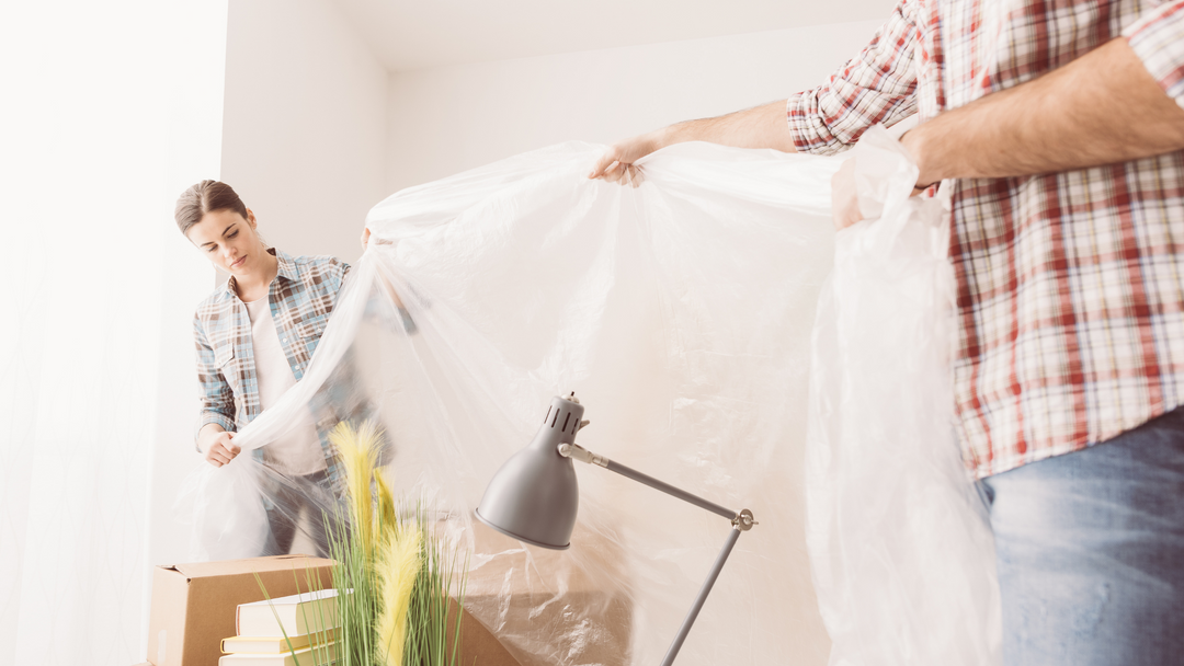 male and female using dust sheet to cover furniture in preparation of house decorating