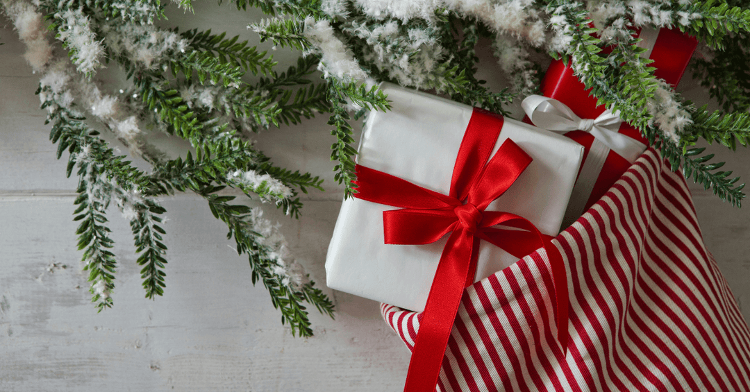 red striped christmas stocking with white gift hanging out with red satin bow tied around it