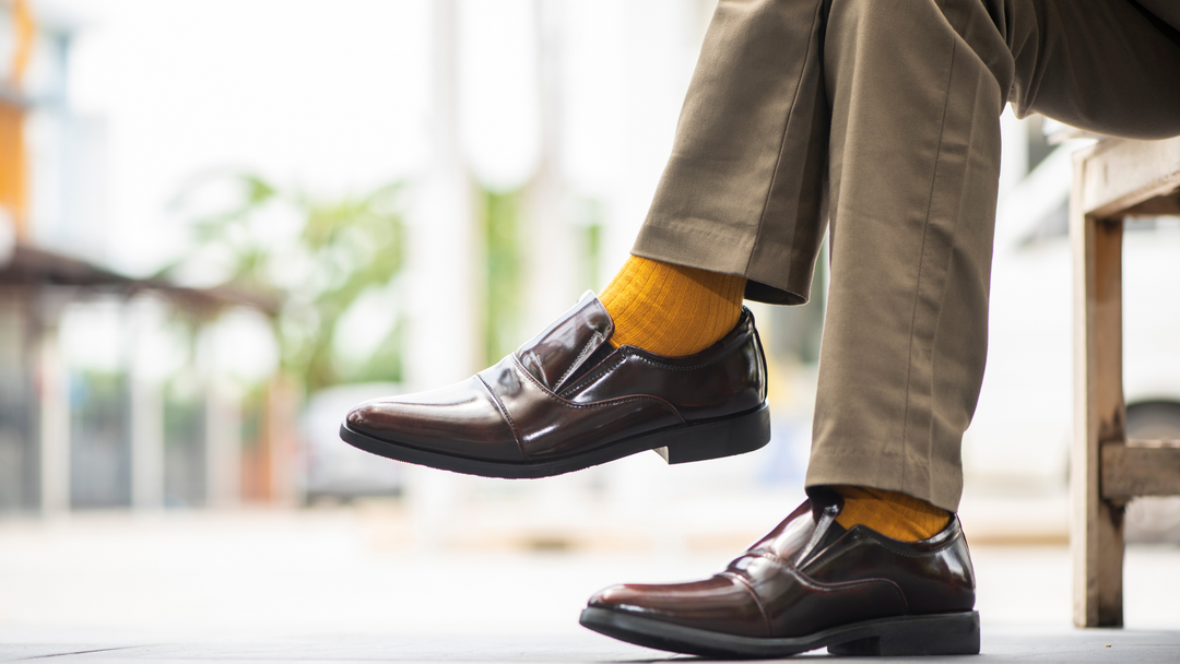 man sitting on a bench wearing straight leg trousers with yellow socks