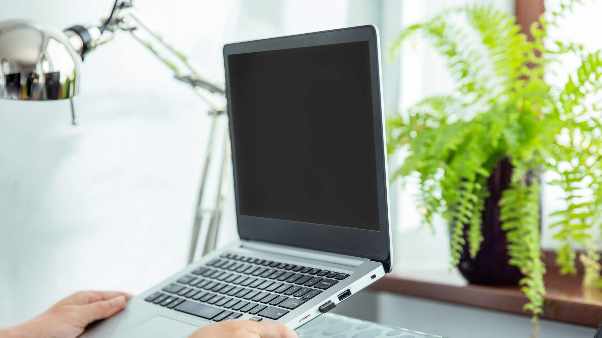 person placing laptop down on laptop stand in home office