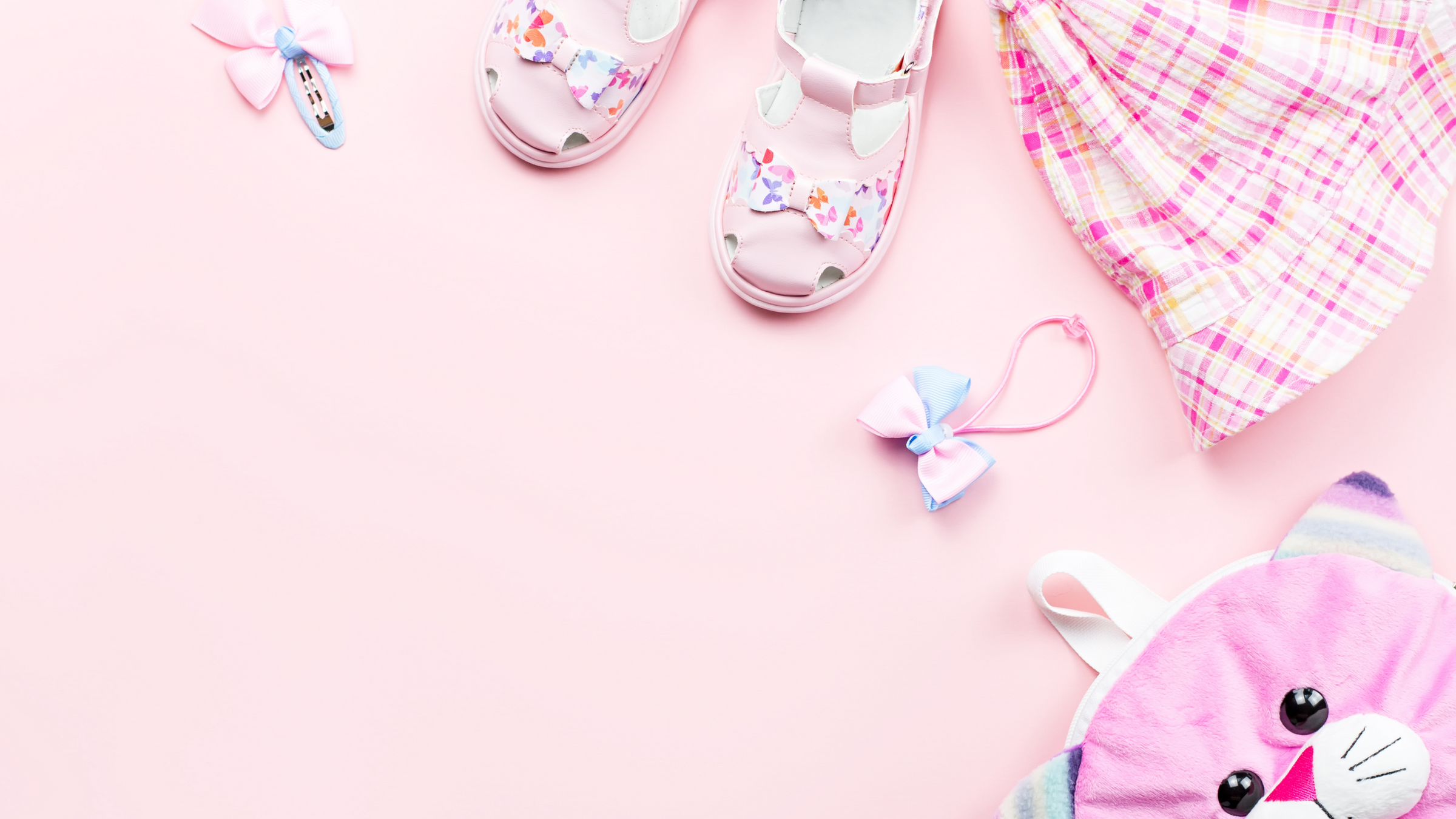 pink background with kids pink summer hat, pink shoes, pain hair accessories and cat bag