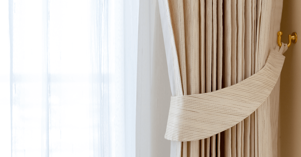 sheer panel curtains on window with natural colour curtains draped backwards with tie panel
