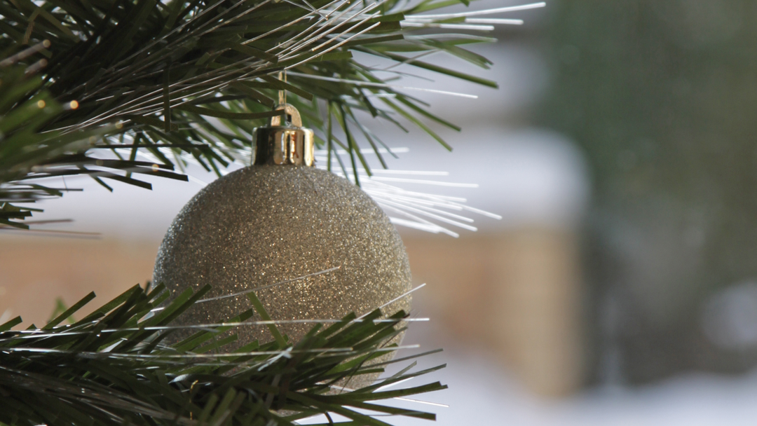 close up of christmas tree with fibre optic lights featuring a gold glitter bauble