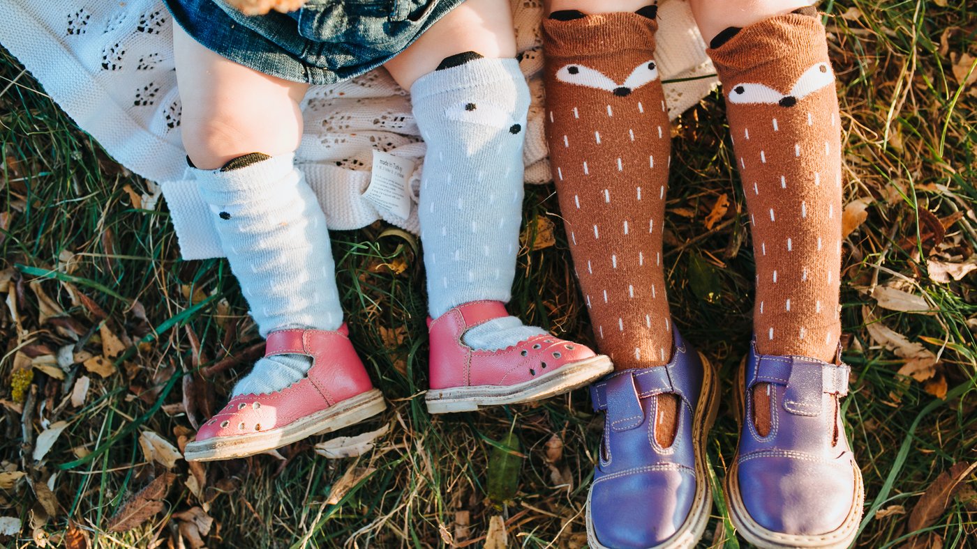 little girls lying on the grass wearing knee high fox socks