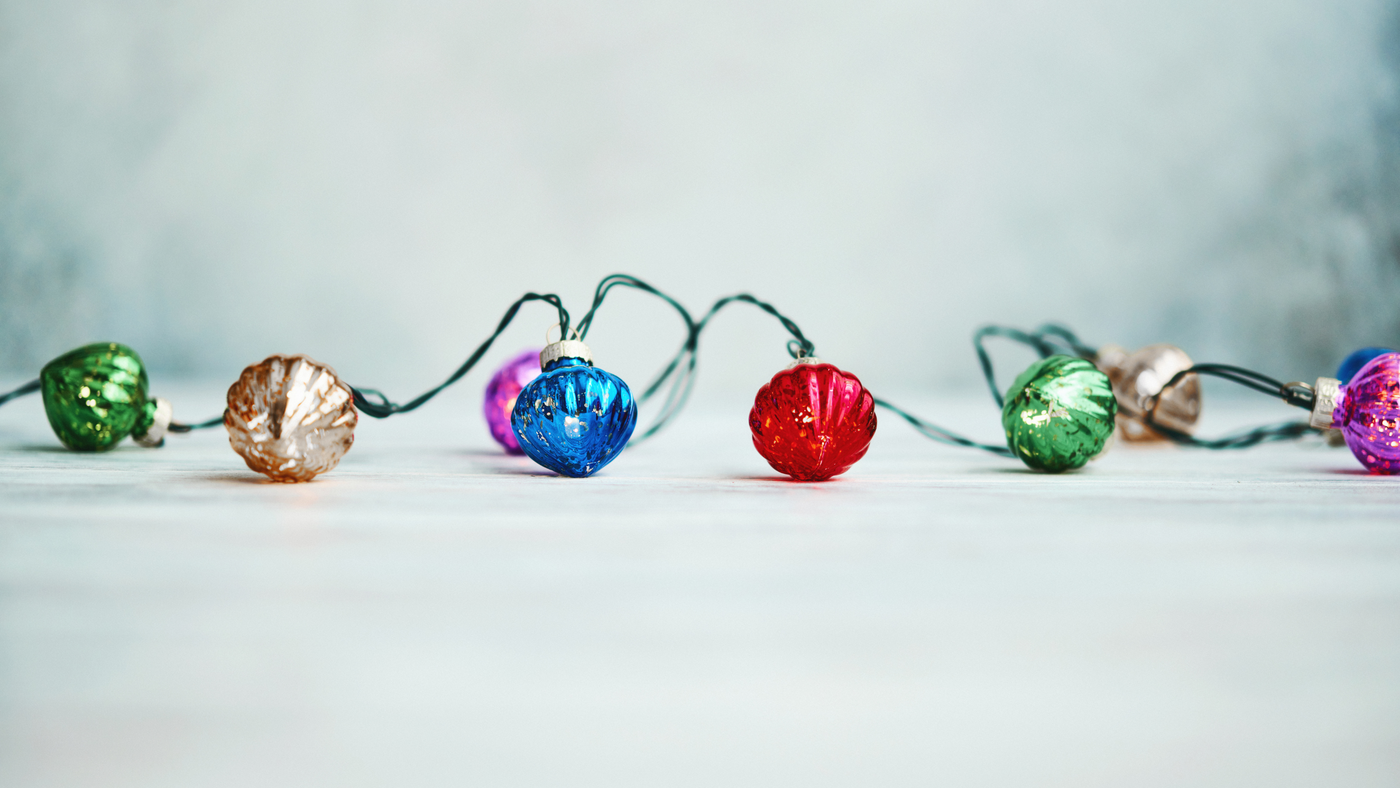 multi coloured christmas bauble string lights on grey background