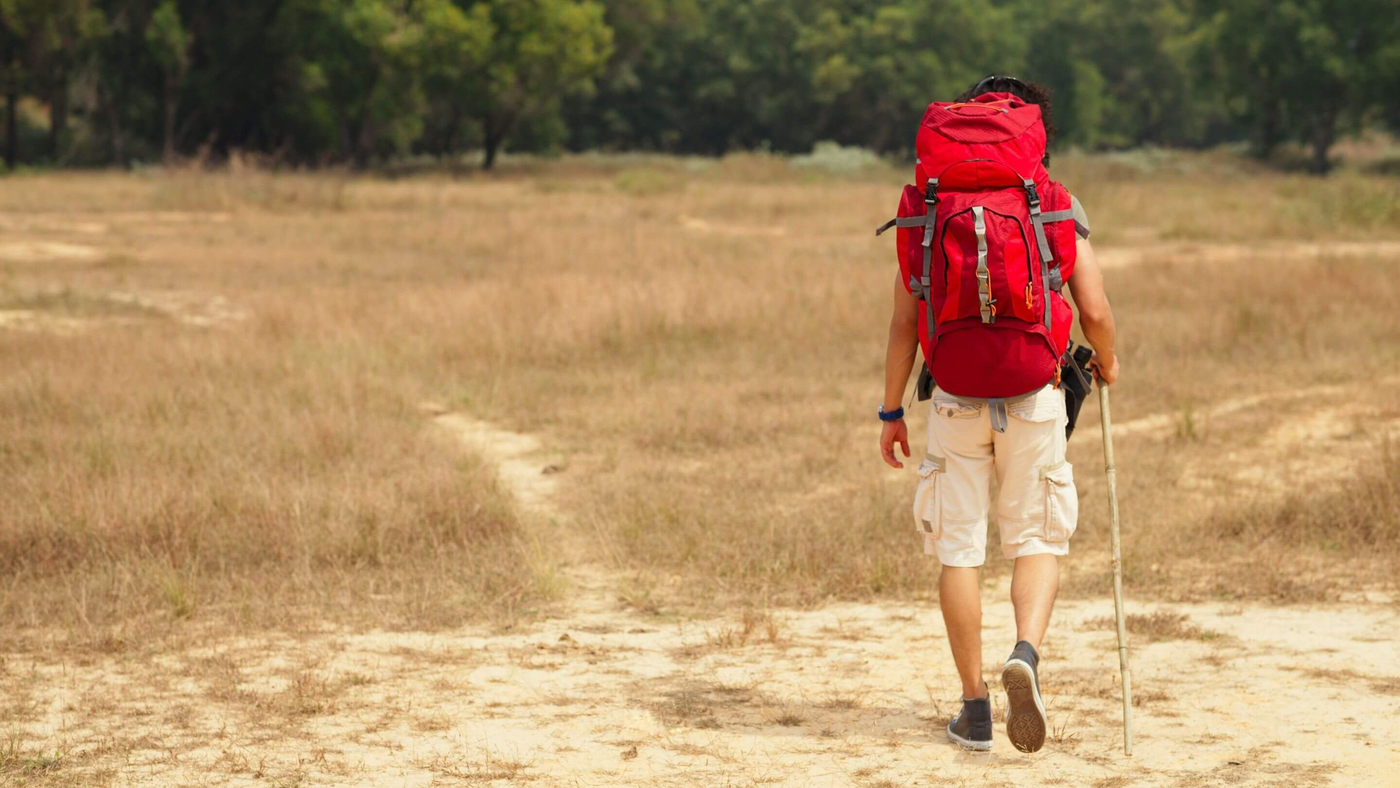 person hiking in desert like location wearing red trekking rucksack