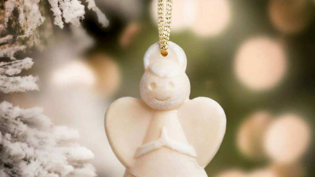 scented angel hanging from christmas tree with lights in the background