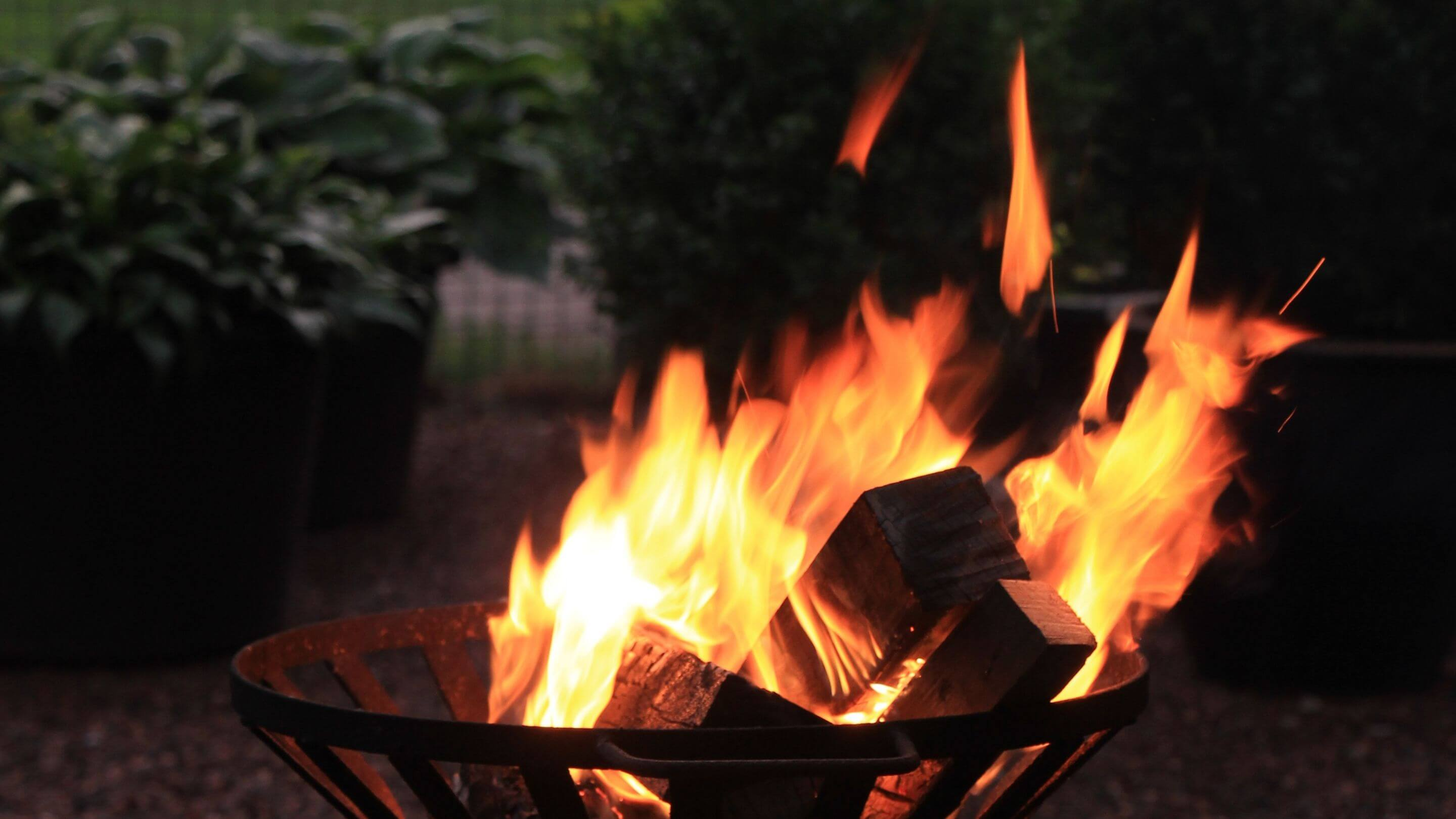 log burner with firelogs kindling at night in garden space