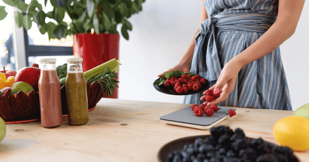 lady weighing raspberries on black slim kitchen scale on top of wooden counter