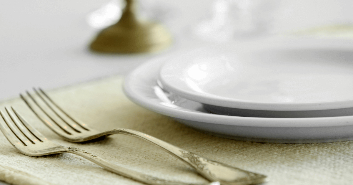white glaze plates on green coloured place mat beside two golden colour forks