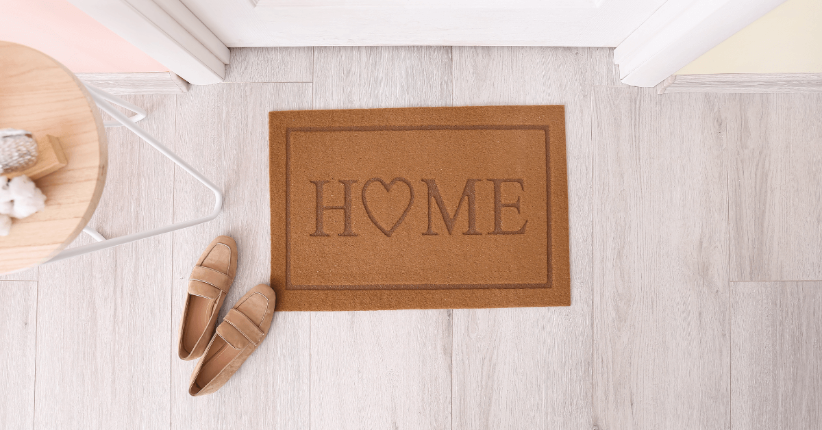 coir home slogan door mat in front of interior door with pink ladies shoes to the left