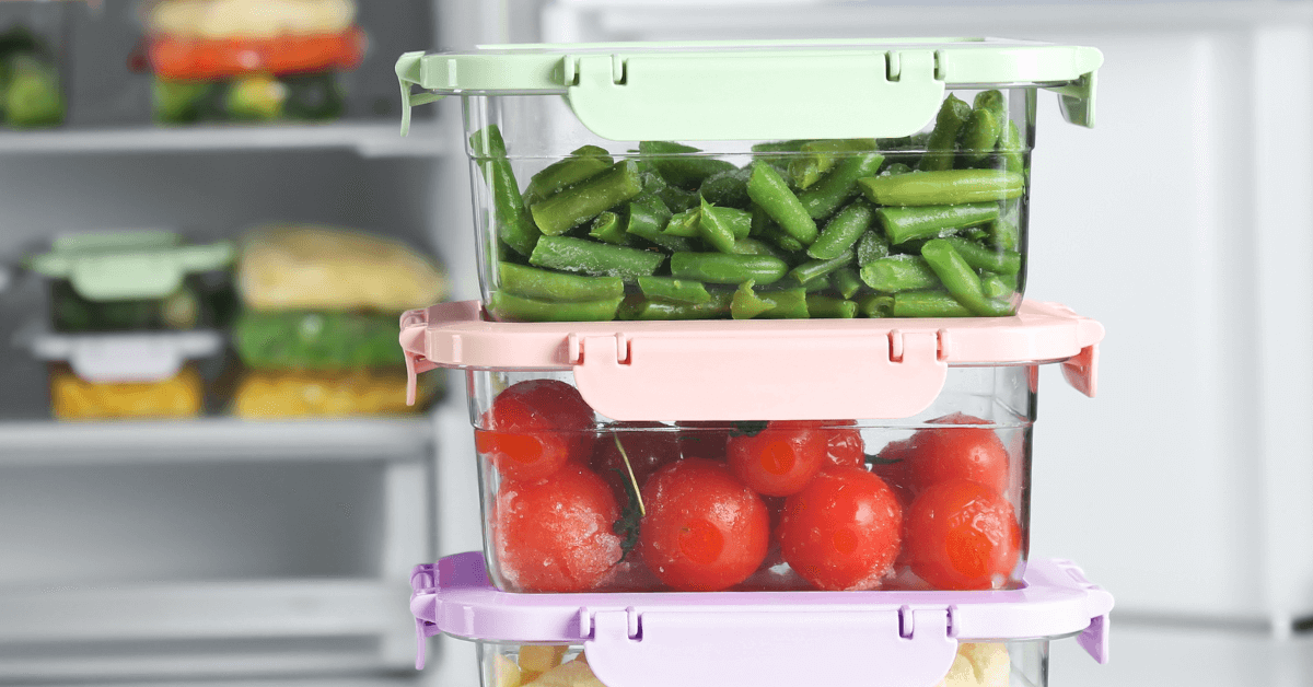 food storage containers in front of fridge packed with fresh tomatoies and green beans