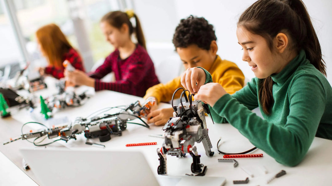 a group of kids playing with science and technology robot toys on desk with laptop and stem tools