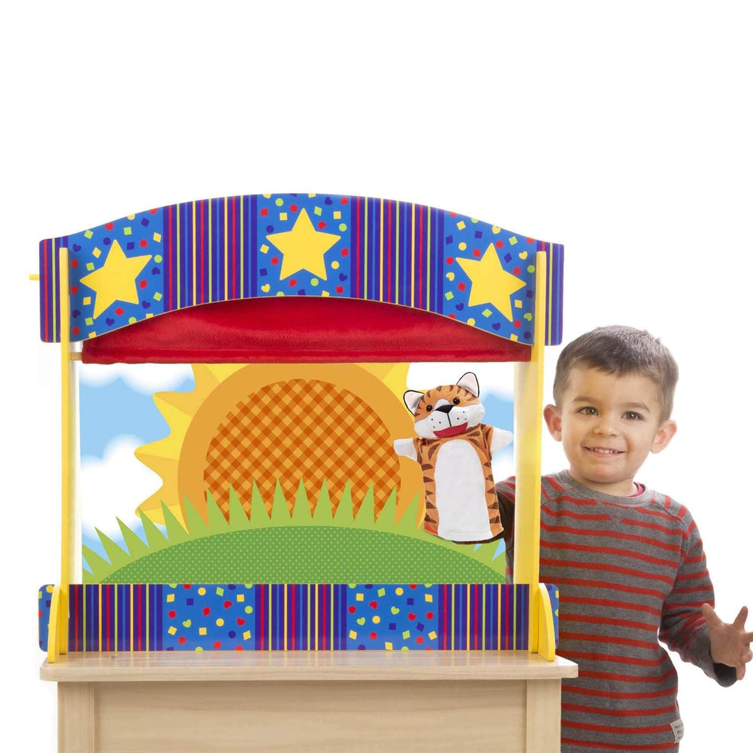 little boy holds tiger puppet inside puppet theatre with sunshine backdrop