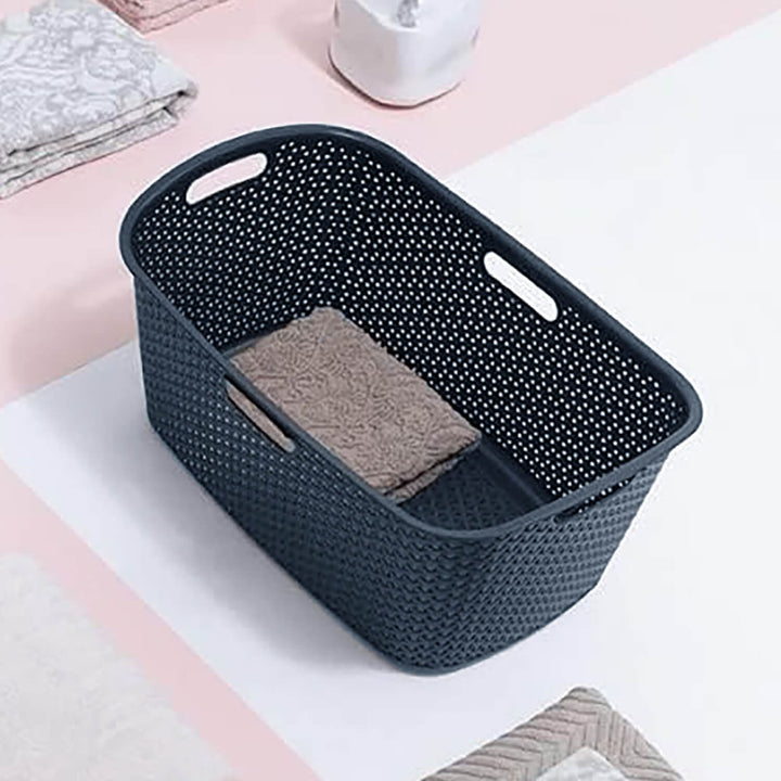 Overhead view of a dark grey Curver laundry basket on a bathroom floor
