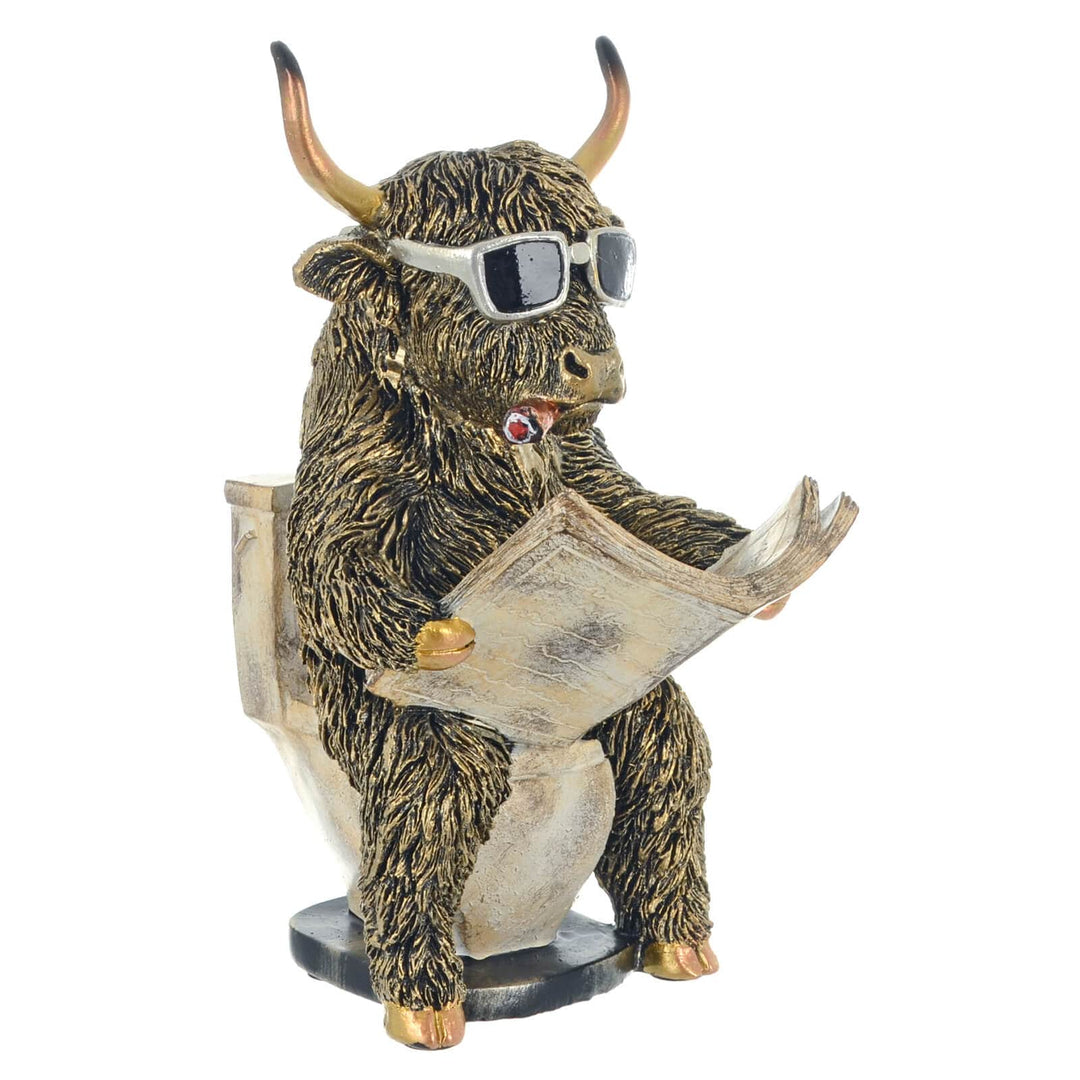 Highland cow figure sitting on a toilet with newspaper