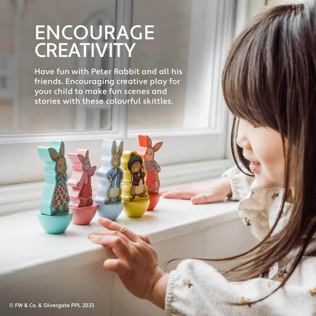 Girl playing with Peter Rabbit character skittles on a windowsill