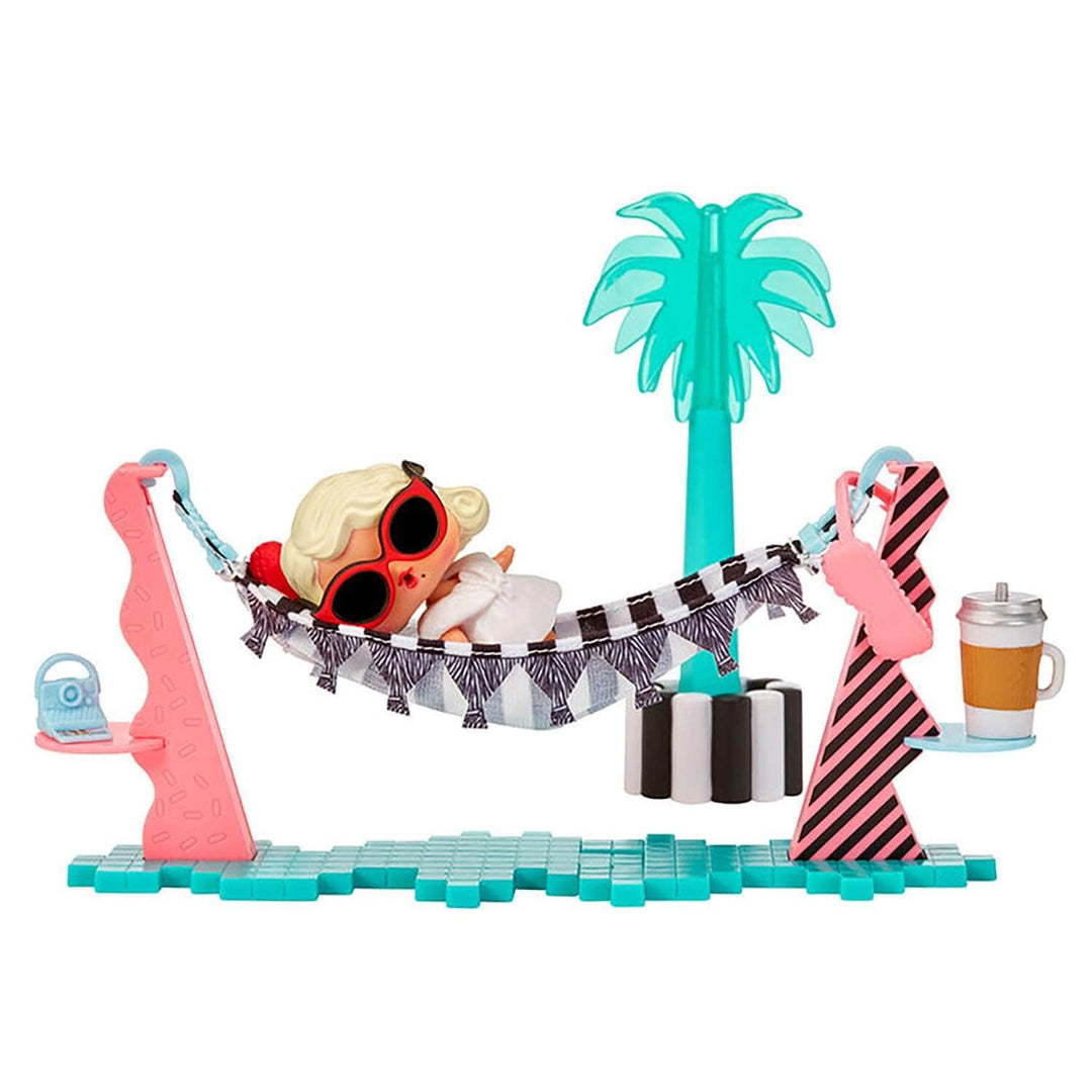 Doll lying on a black and white hammock beside a palm tree