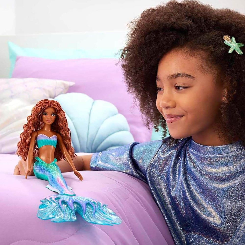 Child playing with a mermaid doll on a bed