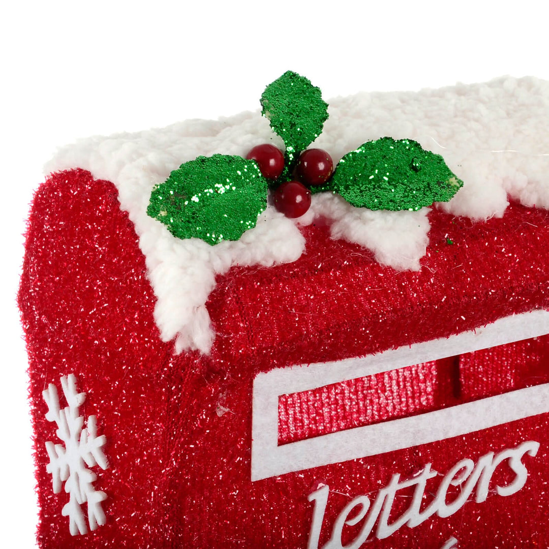 Close up of glittering holly leaves and berries on a letters to Santa post box outdoor Christmas decoration