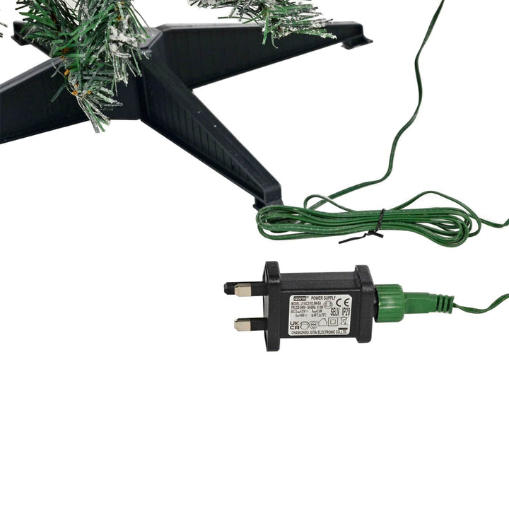 Mains transformer with green wire beside a Christmas tree stand