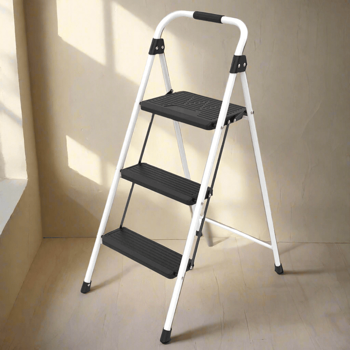 Three-step ladder with black platforms on a beige floor and wall.
