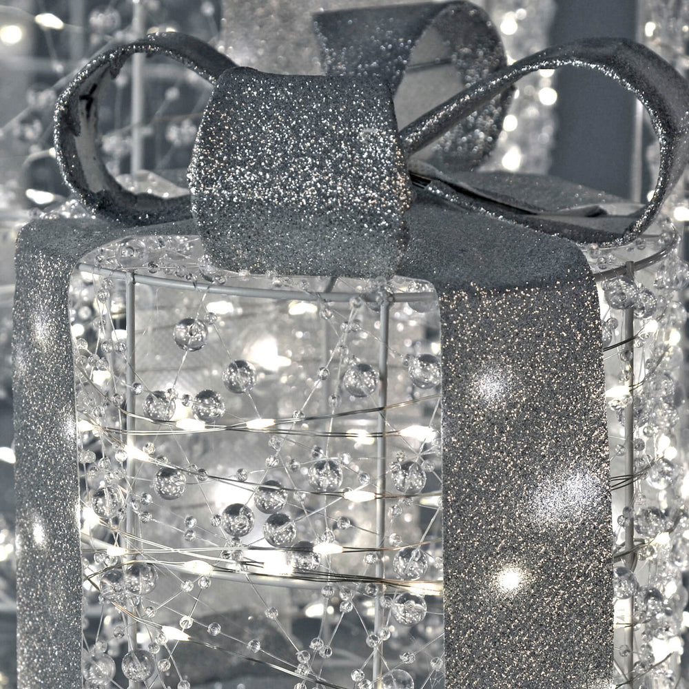 Close up of a glitter bow and ribbon on a beaded gift box with white LED lights