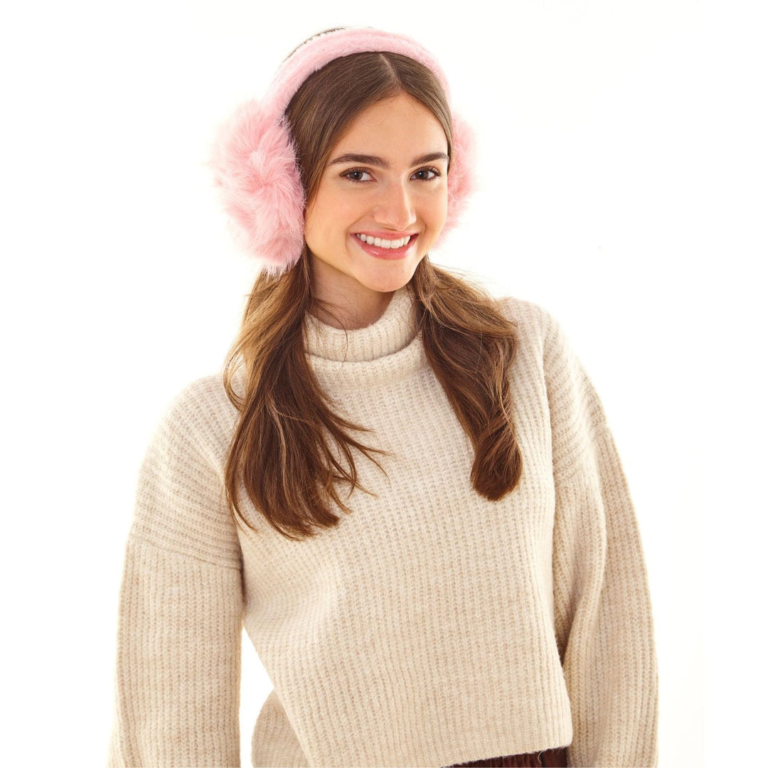 Woman wearing pink fluffy ear muffs and a beige sweater on a white background