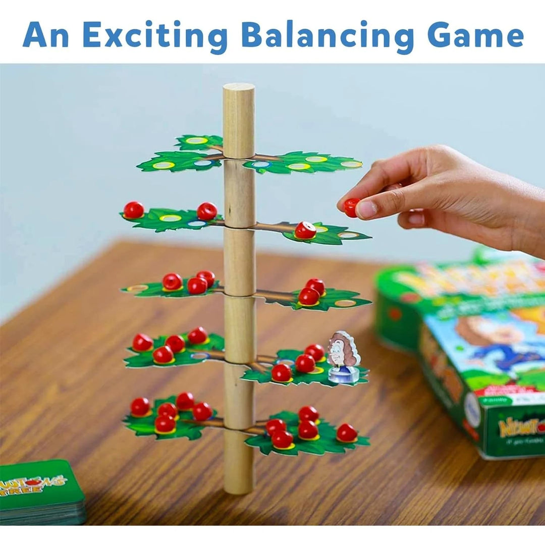 Balancing game with wooden tree and red apples on a wooden table