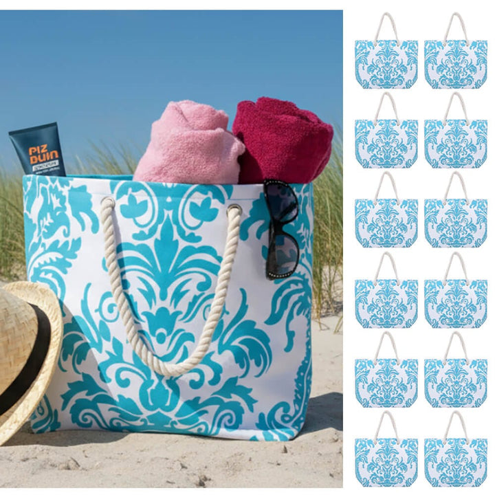 Turquoise blue floral beach bag on sand with sun hat, towels and sunglasses