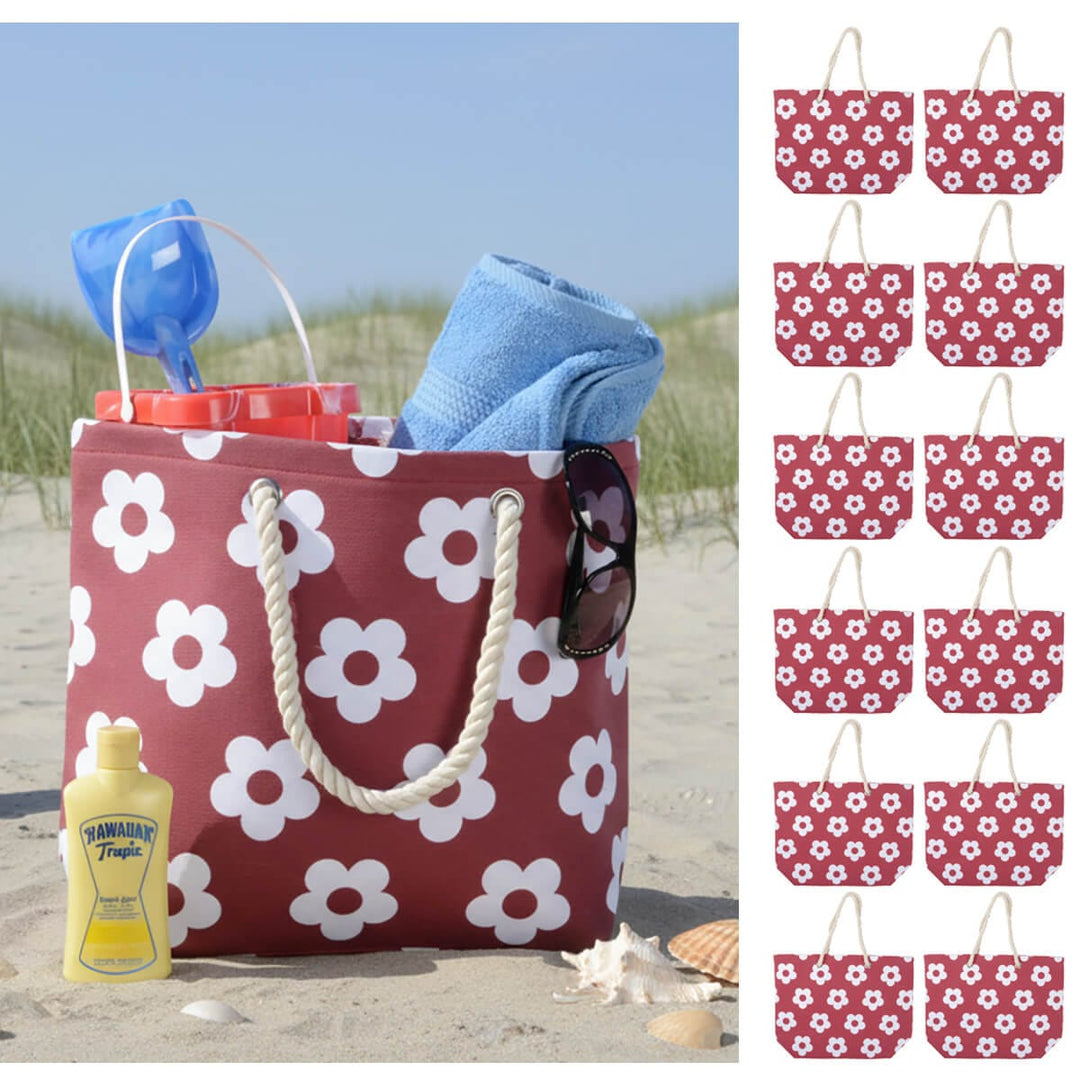 Burgundy colour beach bag with white flower print and rope handles on a beach with shells and 12 small beach bags down one side
