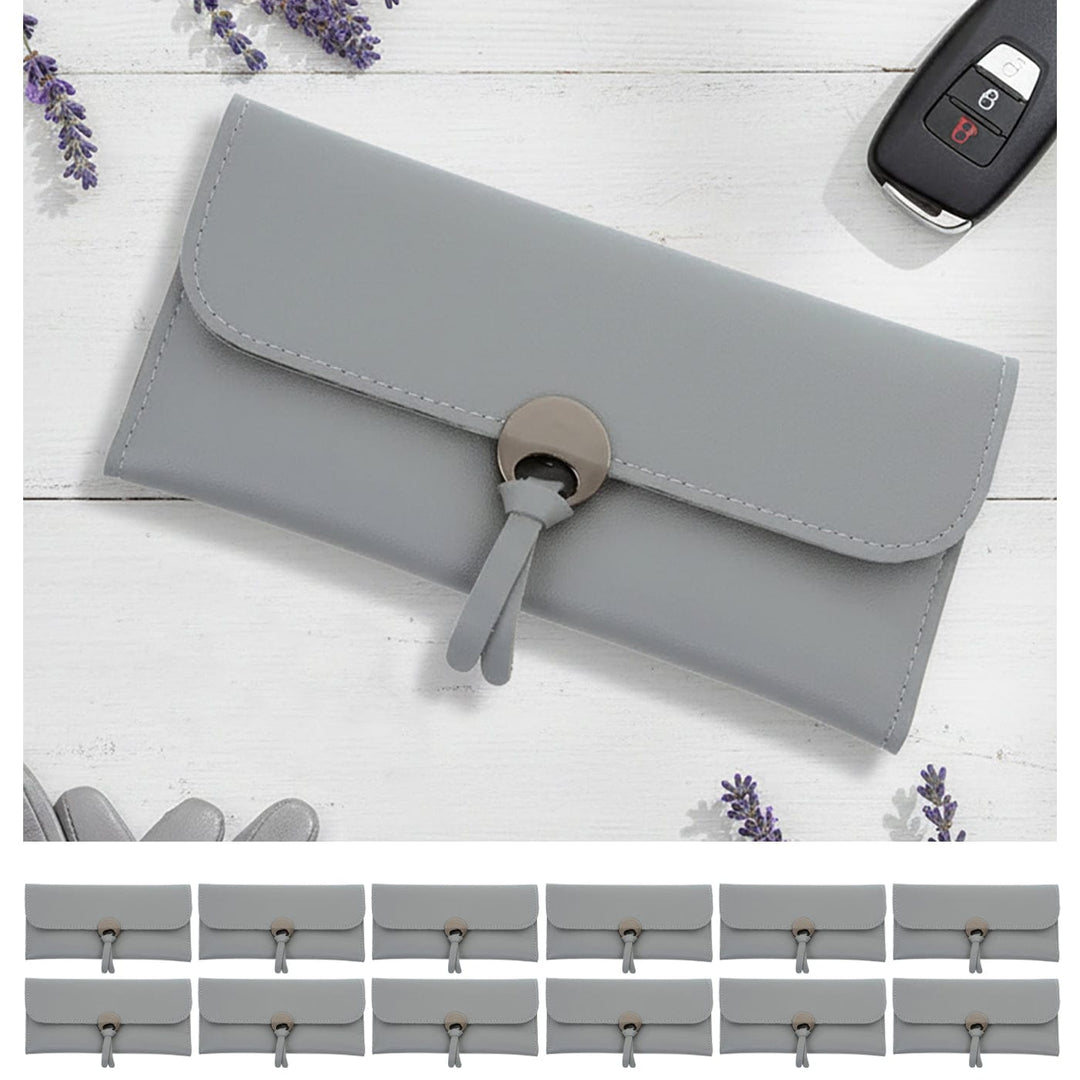 Gray clutch purse with a key fob on a white wooden surface with lavender flowers and 12 small grey purses