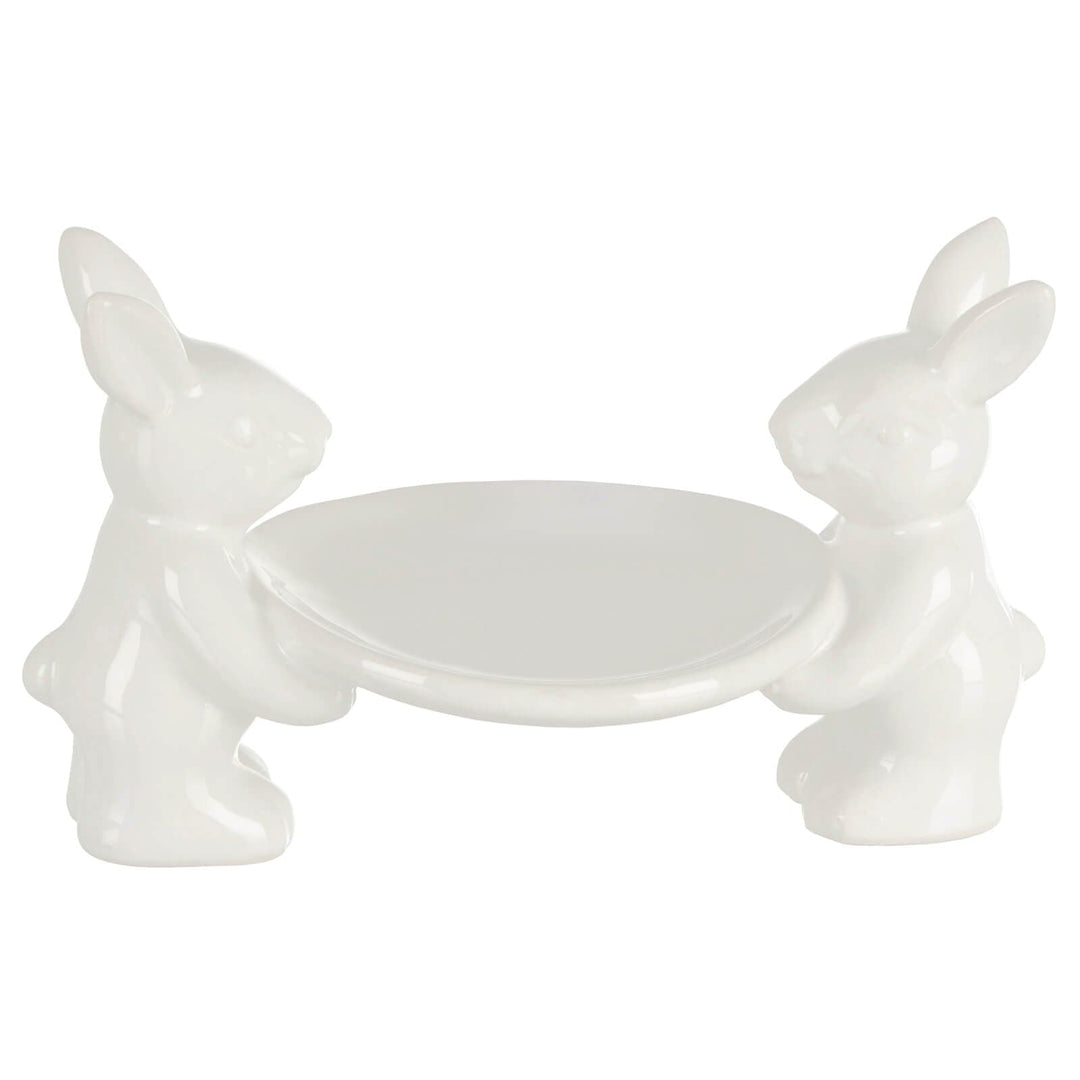 White ceramic cake plate with two rabbit figures on a white background