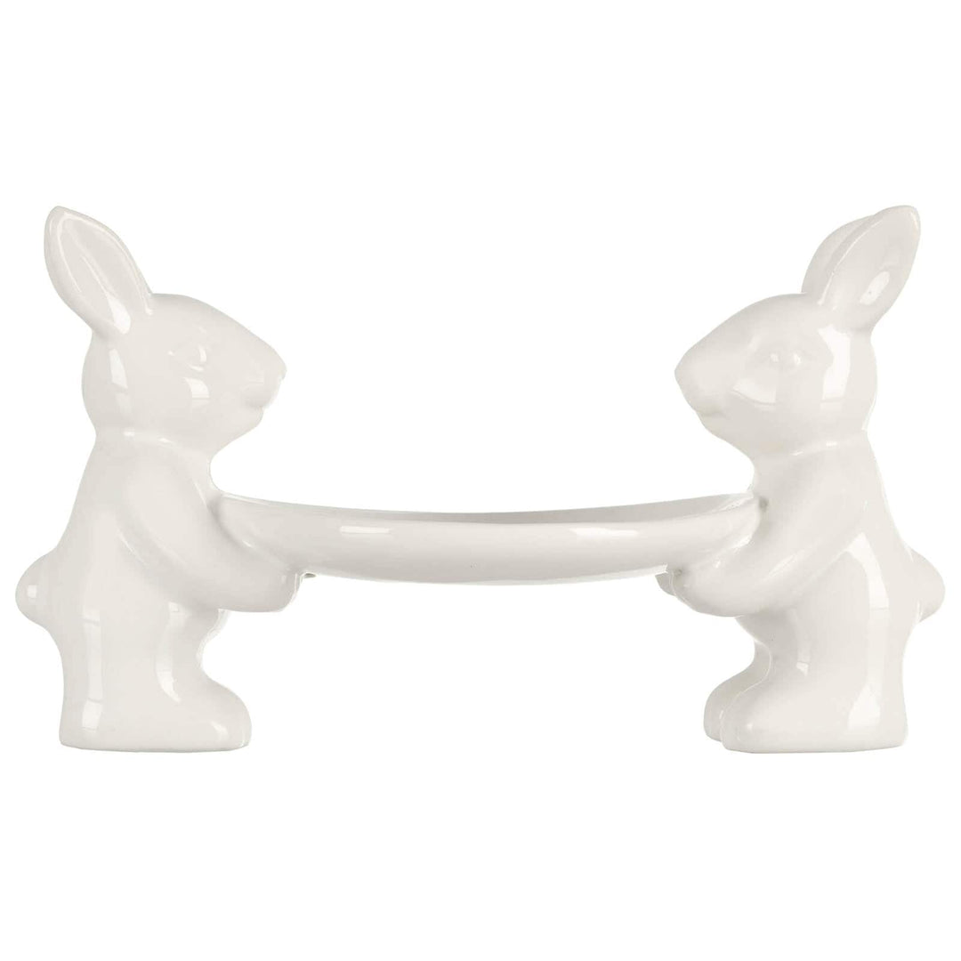 2 white Easter rabbits holding a cake plate on a white background