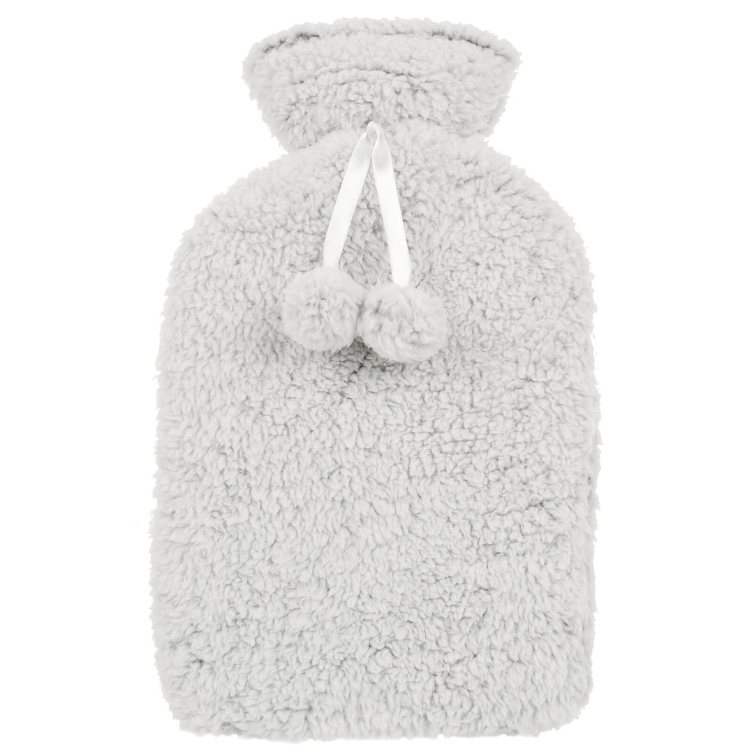 Hot water bottle with thick grey sherpa fleece cover with pom poms on a white background