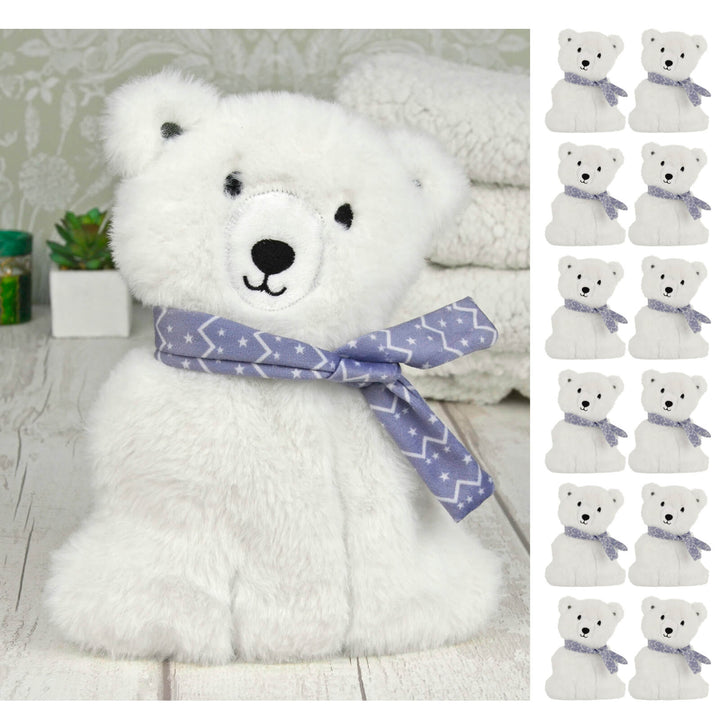 Plush polar bear heat pack on a white washed table with fleece blankets and 12 small polar bears
