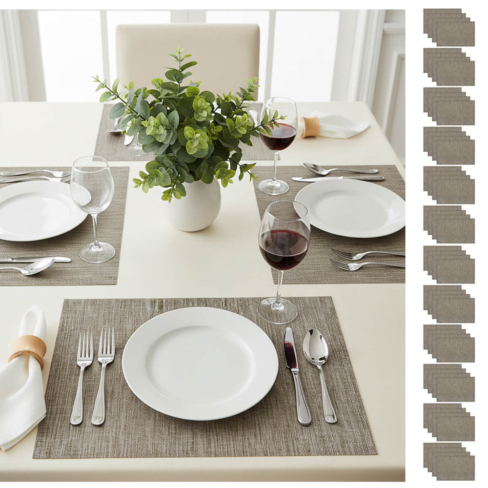 Dining table setting with white plates, silverware, red wine, and a vase of greenery.