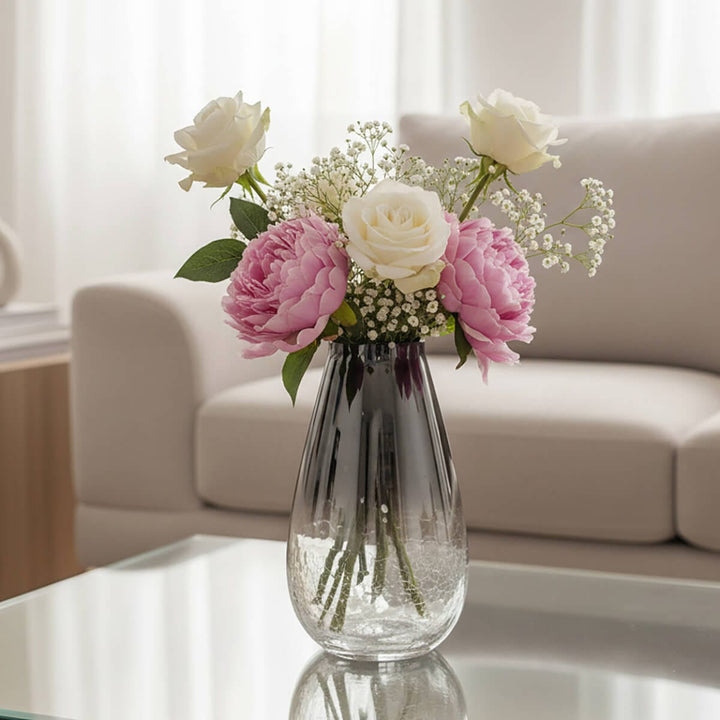 gradient glass vase filled with pink and white flowers on a coffee table with living room background