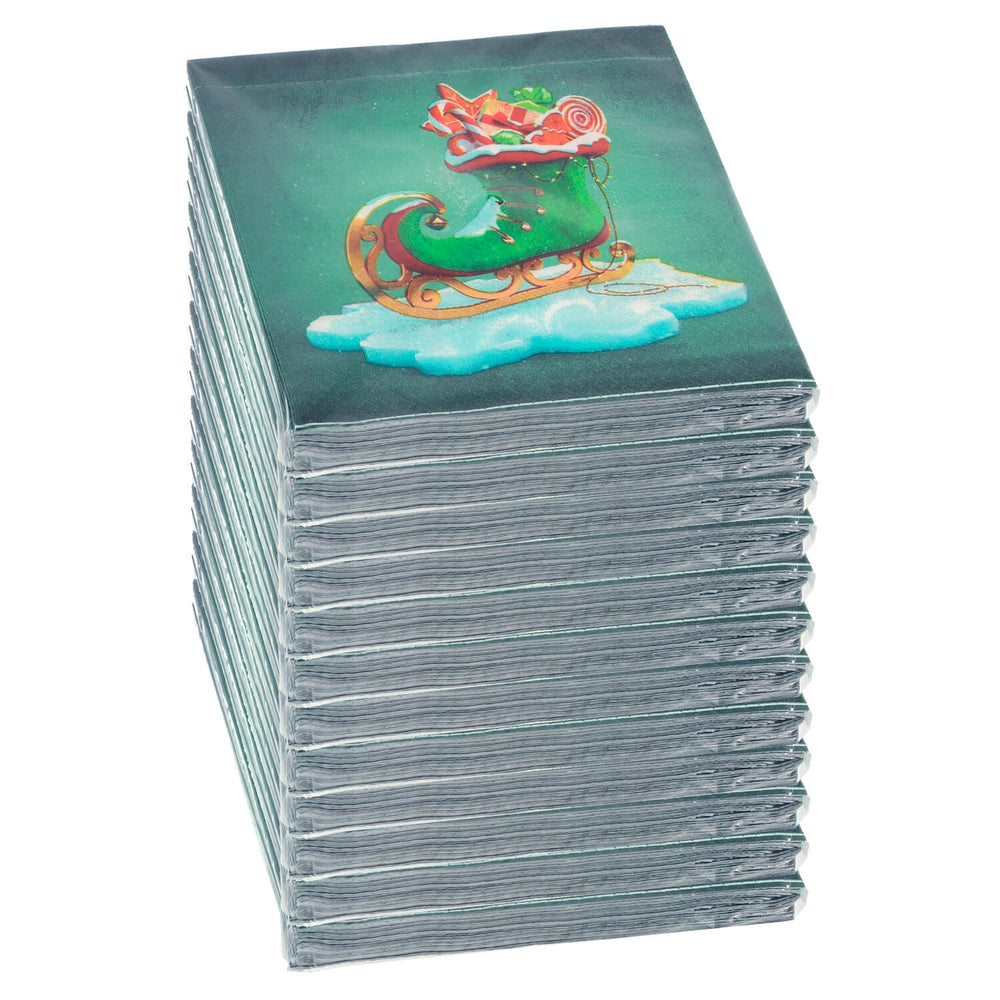 Stack of 12 packs of green ice skate design Christmas napkins on a white background