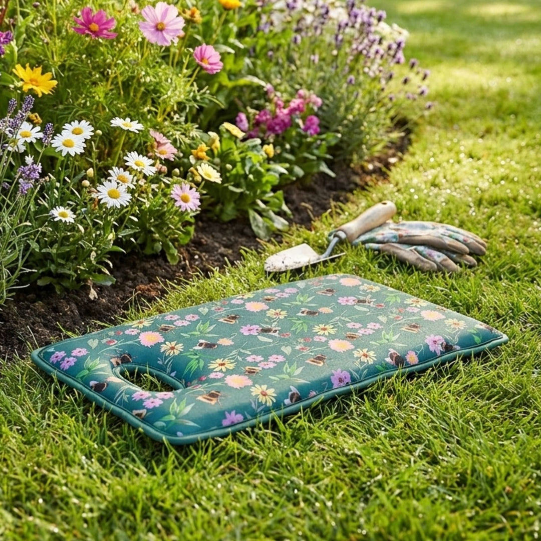 Floral-patterned garden kneeler on grass with gardening tools and flowers in the background