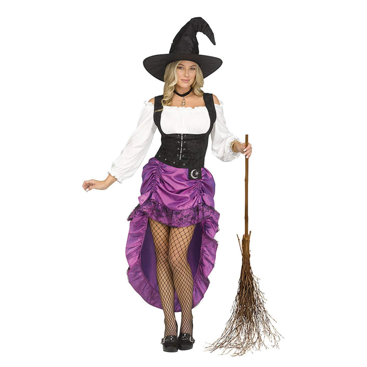 A woman modeling a witch costume on a plain white background, holding a small broom. The costume includes a black pointed witch hat, a white off-the-shoulder blouse, a black corset-style bodice, a purple ruffled high-low skirt with a black lace overlay and a silver crescent moon detail, fishnet tights, and black shoes.