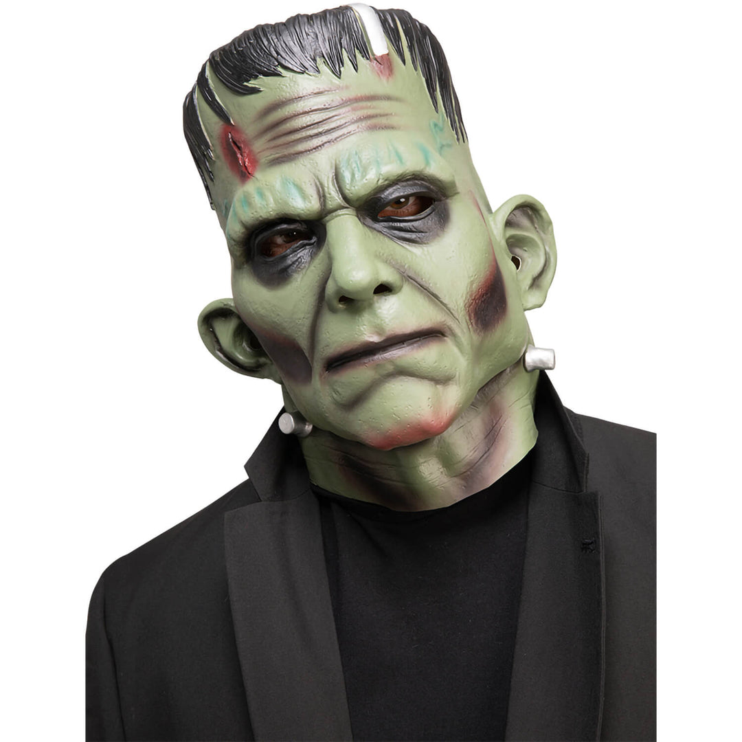 Person wearing a green monster mask with black hair on a white background