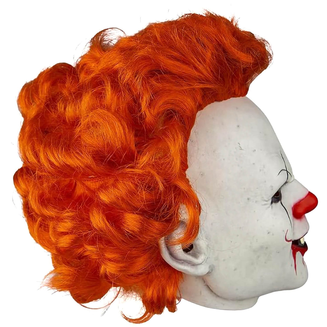 A bright orange curly wig displayed on a white circus clown mask head against a plain white background.